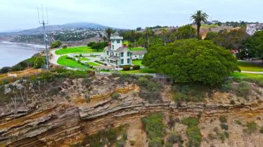 Los Angeles, Kaliforniya 'daki Point Fermin' in alçak hava manzarası, engebeli okyanus kayalıkları, çarpan dalgalar ve karamsar bulutlu kıyı manzarası