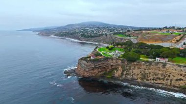 Los Angeles, Kaliforniya 'daki Point Fermin' in alçak hava manzarası, engebeli okyanus kayalıkları, çarpan dalgalar ve karamsar bulutlu kıyı manzarası