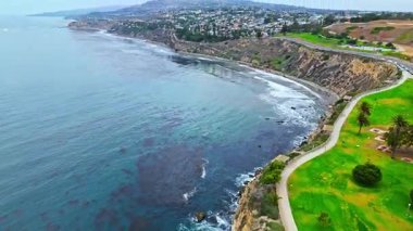 Los Angeles, Kaliforniya 'daki Point Fermin' in alçak hava manzarası, engebeli okyanus kayalıkları, çarpan dalgalar ve karamsar bulutlu kıyı manzarası