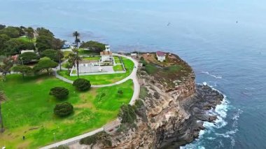Los Angeles, Kaliforniya 'daki Point Fermin' in alçak hava manzarası, engebeli okyanus kayalıkları, çarpan dalgalar ve karamsar bulutlu kıyı manzarası