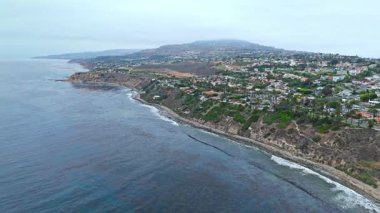 Los Angeles, Kaliforniya 'daki Point Fermin' in alçak hava manzarası, engebeli okyanus kayalıkları, çarpan dalgalar ve karamsar bulutlu kıyı manzarası