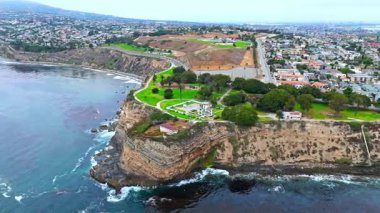 Los Angeles, Kaliforniya 'daki Point Fermin' in alçak hava manzarası, engebeli okyanus kayalıkları, çarpan dalgalar ve karamsar bulutlu kıyı manzarası