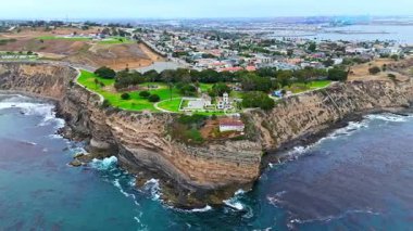 Los Angeles, Kaliforniya 'daki Point Fermin' in alçak hava manzarası, engebeli okyanus kayalıkları, çarpan dalgalar ve karamsar bulutlu kıyı manzarası