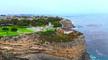 Los Angeles, Kaliforniya 'daki Point Fermin' in alçak hava manzarası, engebeli okyanus kayalıkları, çarpan dalgalar ve karamsar bulutlu kıyı manzarası