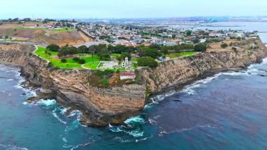 Los Angeles, Kaliforniya 'daki Point Fermin' in alçak hava manzarası, engebeli okyanus kayalıkları, çarpan dalgalar ve karamsar bulutlu kıyı manzarası