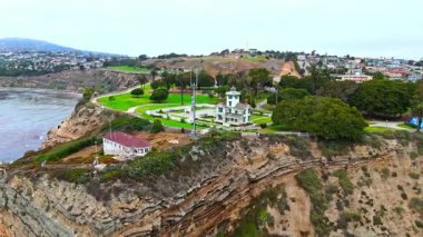 Los Angeles, Kaliforniya 'daki Point Fermin' in alçak hava manzarası, engebeli okyanus kayalıkları, çarpan dalgalar ve karamsar bulutlu kıyı manzarası