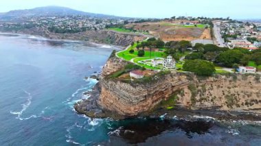 Los Angeles, Kaliforniya 'daki Point Fermin' in alçak hava manzarası, engebeli okyanus kayalıkları, çarpan dalgalar ve karamsar bulutlu kıyı manzarası