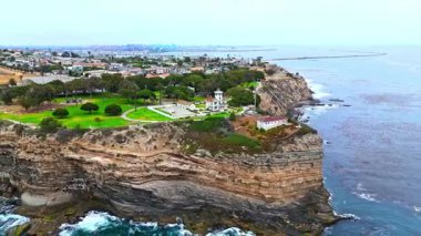 Los Angeles, Kaliforniya 'daki Point Fermin' in alçak hava manzarası, engebeli okyanus kayalıkları, çarpan dalgalar ve karamsar bulutlu kıyı manzarası
