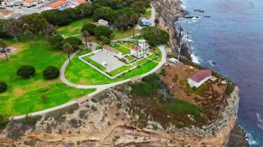 Los Angeles, Kaliforniya 'daki Point Fermin' in alçak hava manzarası, engebeli okyanus kayalıkları, çarpan dalgalar ve karamsar bulutlu kıyı manzarası