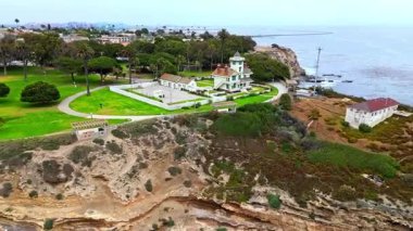 Los Angeles, Kaliforniya 'daki Point Fermin' in alçak hava manzarası, engebeli okyanus kayalıkları, çarpan dalgalar ve karamsar bulutlu kıyı manzarası