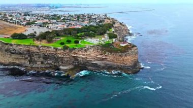 Los Angeles, Kaliforniya 'daki Point Fermin' in alçak hava manzarası, engebeli okyanus kayalıkları, çarpan dalgalar ve karamsar bulutlu kıyı manzarası