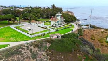 Los Angeles, Kaliforniya 'daki Point Fermin' in alçak hava manzarası, engebeli okyanus kayalıkları, çarpan dalgalar ve karamsar bulutlu kıyı manzarası