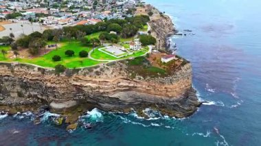 Los Angeles, Kaliforniya 'daki Point Fermin' in alçak hava manzarası, engebeli okyanus kayalıkları, çarpan dalgalar ve karamsar bulutlu kıyı manzarası