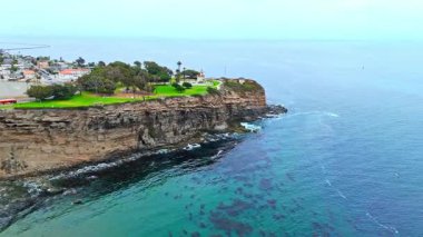Los Angeles, Kaliforniya 'daki Point Fermin' in alçak hava manzarası, engebeli okyanus kayalıkları, çarpan dalgalar ve karamsar bulutlu kıyı manzarası