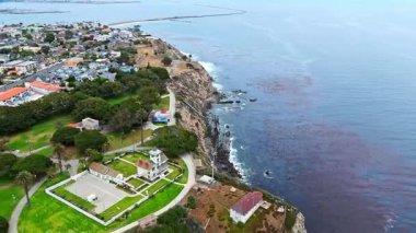 Los Angeles, Kaliforniya 'daki Point Fermin' in alçak hava manzarası, engebeli okyanus kayalıkları, çarpan dalgalar ve karamsar bulutlu kıyı manzarası