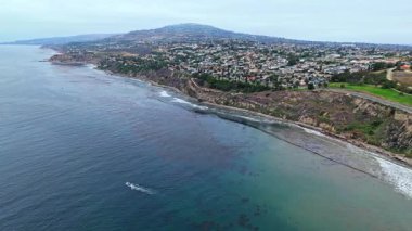 Los Angeles, Kaliforniya 'daki Point Fermin' in alçak hava manzarası, engebeli okyanus kayalıkları, çarpan dalgalar ve karamsar bulutlu kıyı manzarası