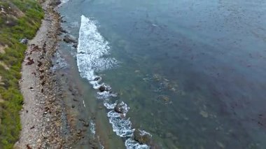 Los Angeles, Kaliforniya 'daki Point Fermin' in alçak hava manzarası, engebeli okyanus kayalıkları, çarpan dalgalar ve karamsar bulutlu kıyı manzarası