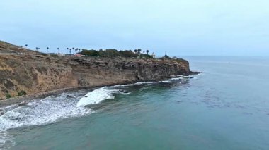 Los Angeles, Kaliforniya 'daki Point Fermin' in alçak hava manzarası, engebeli okyanus kayalıkları, çarpan dalgalar ve karamsar bulutlu kıyı manzarası