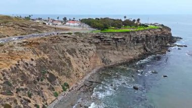 Los Angeles, Kaliforniya 'daki Point Fermin' in alçak hava manzarası, engebeli okyanus kayalıkları, çarpan dalgalar ve karamsar bulutlu kıyı manzarası