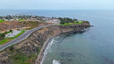 Los Angeles, Kaliforniya 'daki Point Fermin' in alçak hava manzarası, engebeli okyanus kayalıkları, çarpan dalgalar ve karamsar bulutlu kıyı manzarası