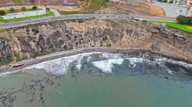Los Angeles, Kaliforniya 'daki Point Fermin' in alçak hava manzarası, engebeli okyanus kayalıkları, çarpan dalgalar ve karamsar bulutlu kıyı manzarası