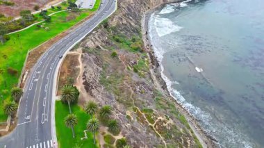 Los Angeles, Kaliforniya 'daki Point Fermin' in alçak hava manzarası, engebeli okyanus kayalıkları, çarpan dalgalar ve karamsar bulutlu kıyı manzarası