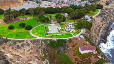 Los Angeles, Kaliforniya 'daki Point Fermin' in alçak hava manzarası, engebeli okyanus kayalıkları, çarpan dalgalar ve karamsar bulutlu kıyı manzarası