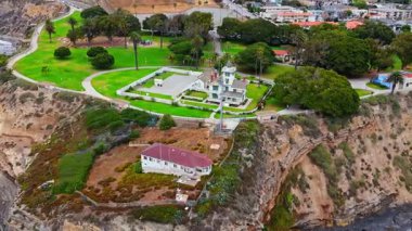 Los Angeles, Kaliforniya 'daki Point Fermin' in alçak hava manzarası, engebeli okyanus kayalıkları, çarpan dalgalar ve karamsar bulutlu kıyı manzarası