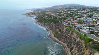 Los Angeles, Kaliforniya 'daki Point Fermin' in alçak hava manzarası, engebeli okyanus kayalıkları, çarpan dalgalar ve karamsar bulutlu kıyı manzarası