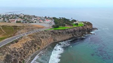 Los Angeles, Kaliforniya 'daki Point Fermin' in alçak hava manzarası, engebeli okyanus kayalıkları, çarpan dalgalar ve karamsar bulutlu kıyı manzarası
