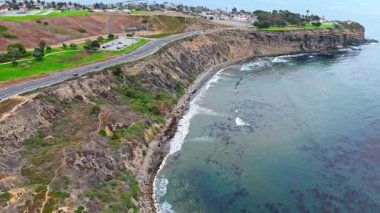Los Angeles, Kaliforniya 'daki Point Fermin' in alçak hava manzarası, engebeli okyanus kayalıkları, çarpan dalgalar ve karamsar bulutlu kıyı manzarası
