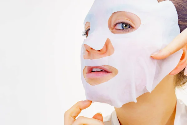 彼女の顔にシートマスクを適用する女性 肌の顔色の世話をする女の子 美容トリートメント スキンケア — ストック写真