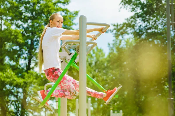 stock image Full body of woman working out in outdoor gym. Girl doing legs exercises on street public equipment on sunny day