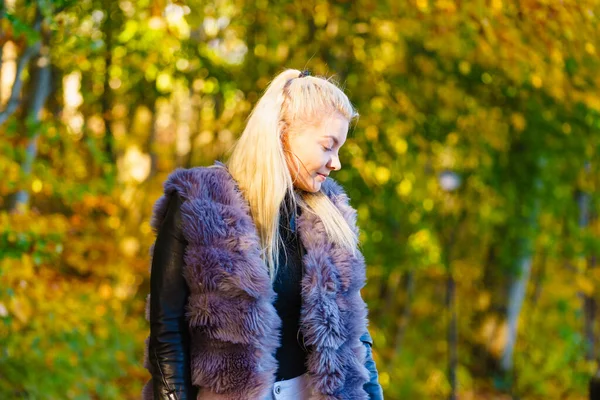 穿着时髦服装的女人在秋天的公园里散步时穿着人造毛皮外套 — 图库照片