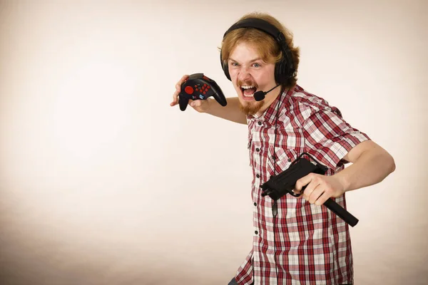 マイクでヘッドフォンを装着した銃を持ったビデオコンソールで遊んでいるオタク青年 ゲームゲーマーの概念 — ストック写真