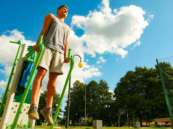 stock image Young handsome man working out in outdoor gym. Sporty guy flexing his muscles on machine. Staying fit and healthy.