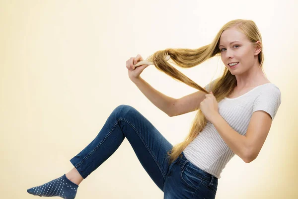 ブロンドの女性は 彼女の非常に長い髪を持ってブラシで 十代の女の子は彼女の髪型をリフレッシュ世話をする ヘアケアのコンセプト — ストック写真