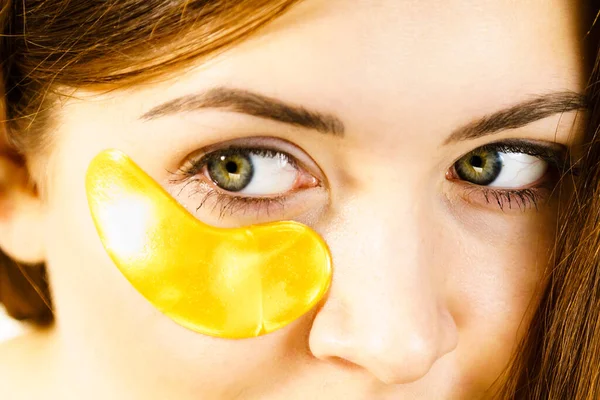 目の下に黄金のコラーゲンパッチを適用する女性 しわや暗い円を削除マスク 女性は目の周りに繊細な肌の世話をする 美容トリートメント — ストック写真