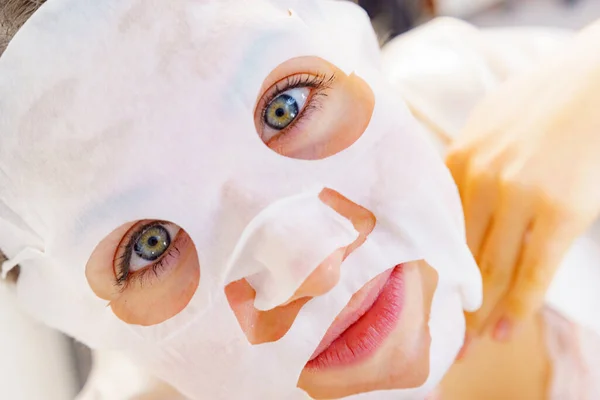 彼女の顔にシートマスクを適用する女性 肌の顔色の世話をする女の子 美容トリートメント スキンケア — ストック写真
