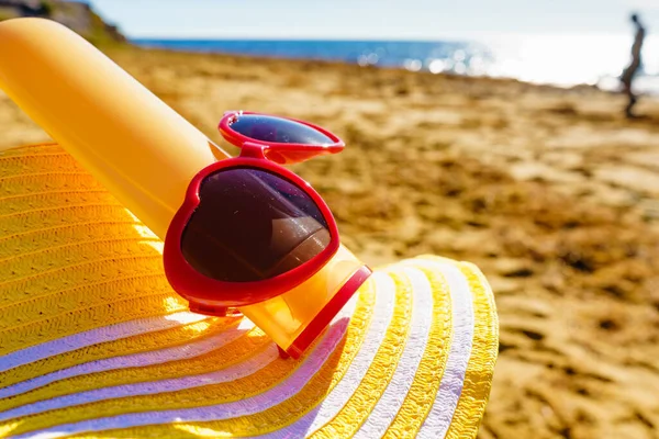 海岸沿いの太陽の保護アクセサリー 砂浜の赤いサングラス 黄色の麦藁帽子と日焼け止めクリームボトル 夏休み — ストック写真