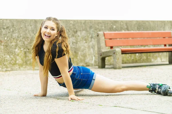 Vrolijke Vrolijke Jonge Vrouw Met Rolschaatsen Die Haar Benen Strekken — Stockfoto