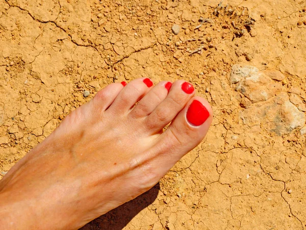 Mujer Pies Bronceados Con Esmalte Uñas Rojo Playa Tierra Seca —  Fotos de Stock