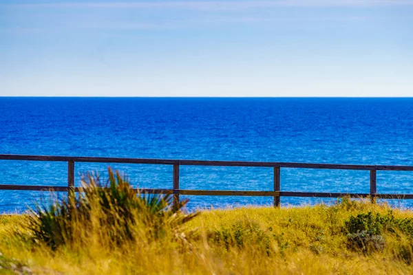 フェンスと穏やかな青い水と海の海岸 — ストック写真