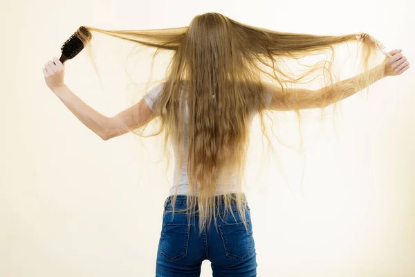 用刷子梳理长发的金发女人 年少时的女孩 头发保养得不好 背景色 — 图库照片