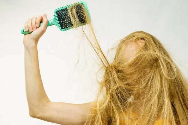 ブロンドの女の子は長い間乱雑な髪を絡ませて大きなブラシを保持します 絡まず 彼女の髪をブラッシング ヘアケア 治療の概念 — ストック写真