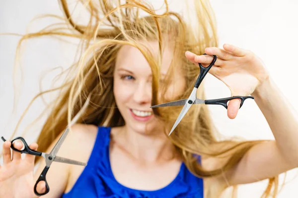 ヘアカットカフヘアケアのコンセプト 長いブロンドの髪の保持はさみを吹いている女の子 作業ツールを示します 通常と薄毛 — ストック写真