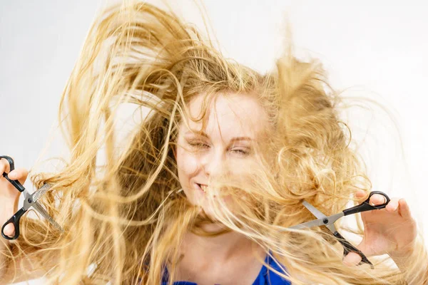 長いブロンドの髪を吹いて女の子は はさみを保持し 作業ツール 通常とチャンクの毛を示しています 新しい髪型を作る ヘアケアのコンセプト — ストック写真