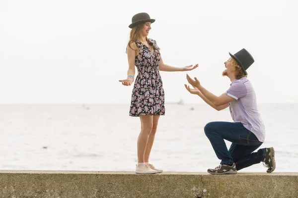 Vintage retro couple, man and woman enjoying their romantic date outside wearing fedora hats by seaside