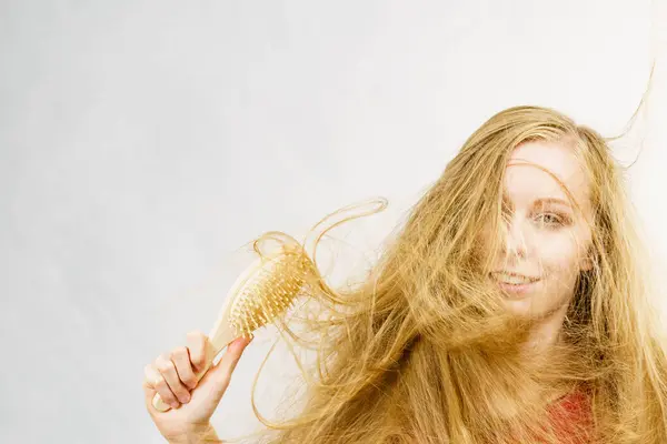 Ξανθιά Κοπέλα Μακριά Μπερδεμένα Μαλλιά Κρατάει Βούρτσα Ξεμπερδεύει Και Βουρτσίζει — Φωτογραφία Αρχείου