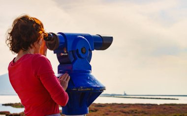 Woman using sightseeing binoculars, tourist telescope, overlooking Las Salinas landscape in Cabo de Gata Nijar Natural Park, Andalucia Spain. Place to visit. Tourism clipart